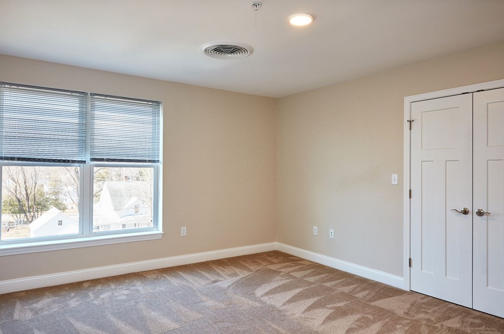 an empty bedroom with a large window and a white door