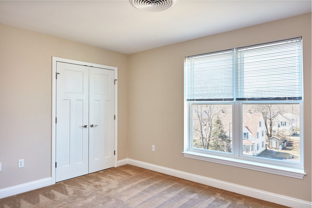 an empty bedroom with a large window and a white door
