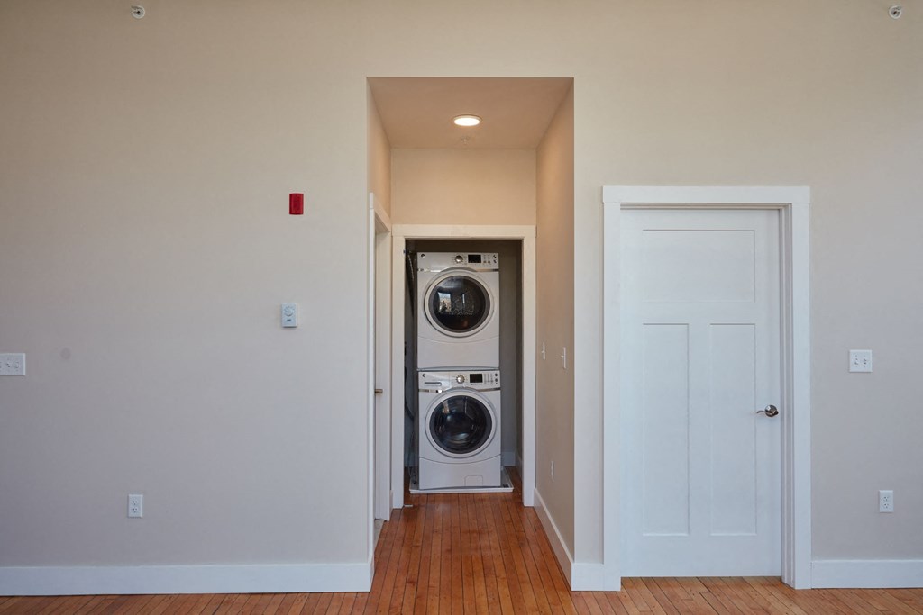 a washer and dryer in a hallway with a door to a laundry room