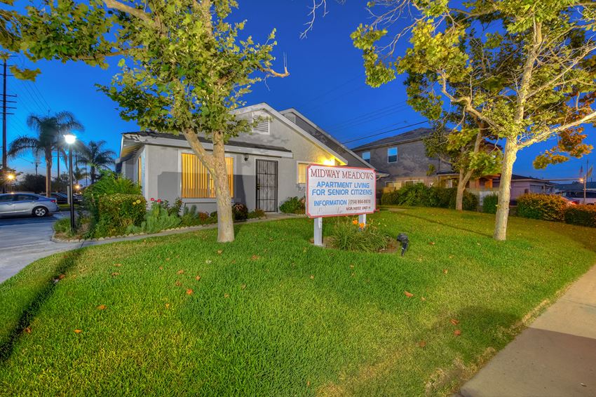 a house with a sign in front of a yard with trees