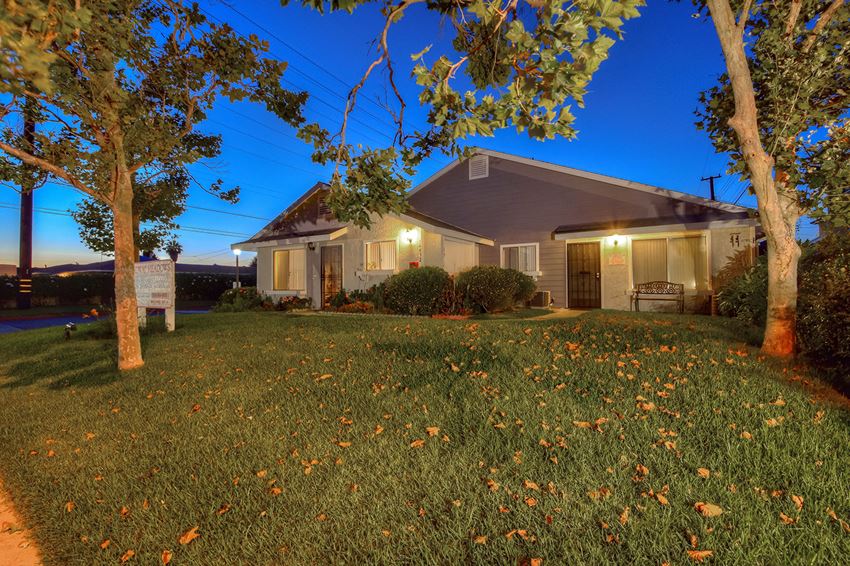 the front of our house at night with trees and grass