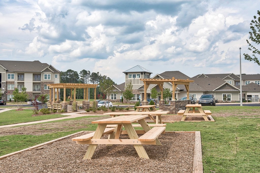 Picnic tables are set up in a grassy area in front of apartment buildings.