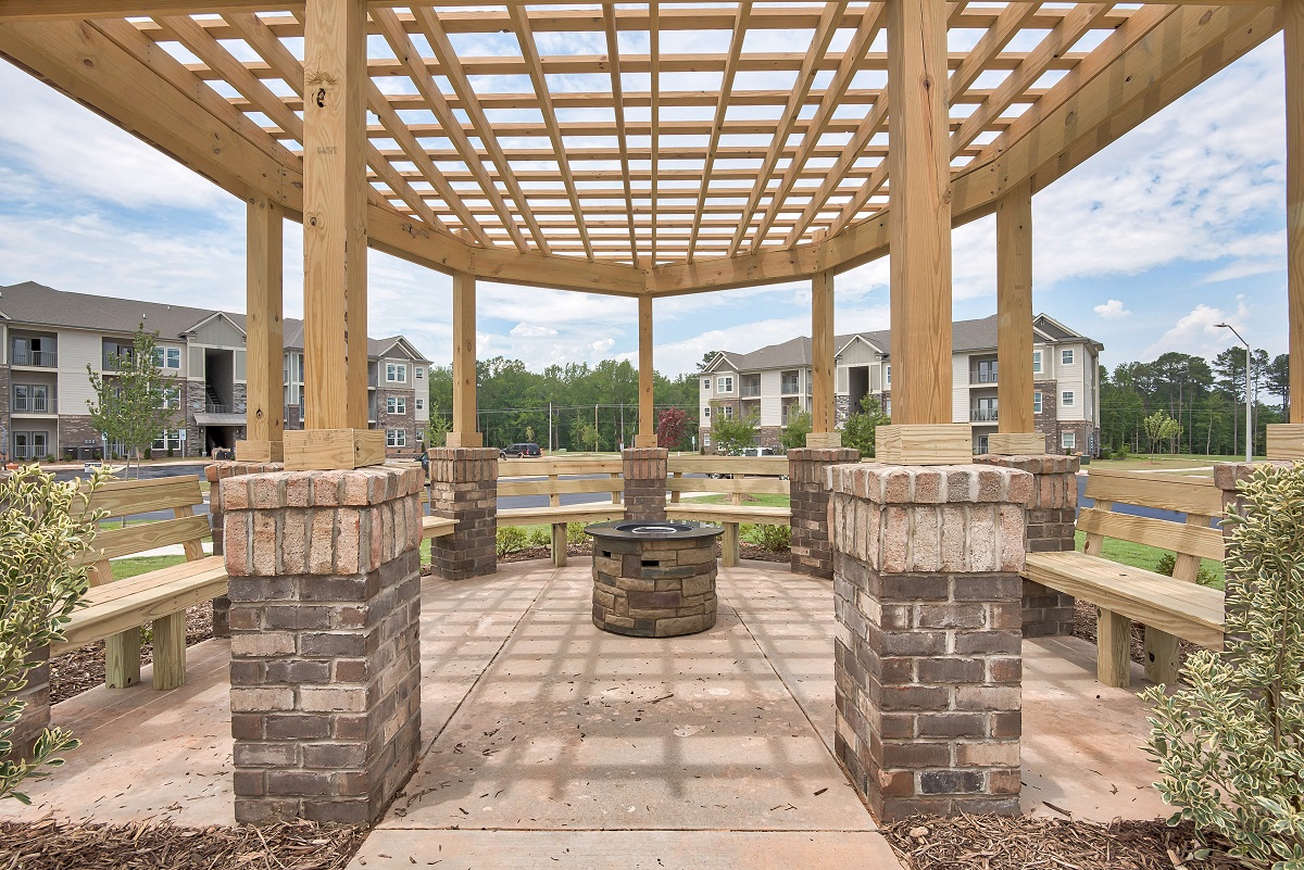 a covered patio with benches and a fire pit