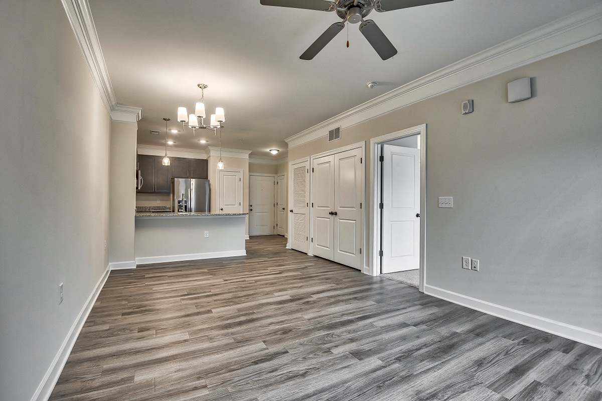 an empty living room with a ceiling fan and a kitchen