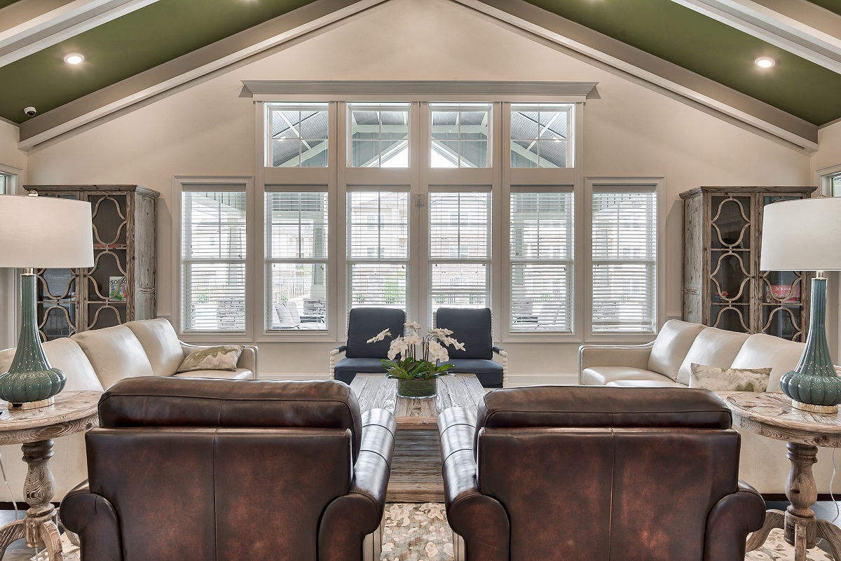 a living room with leather furniture and a large row of windows