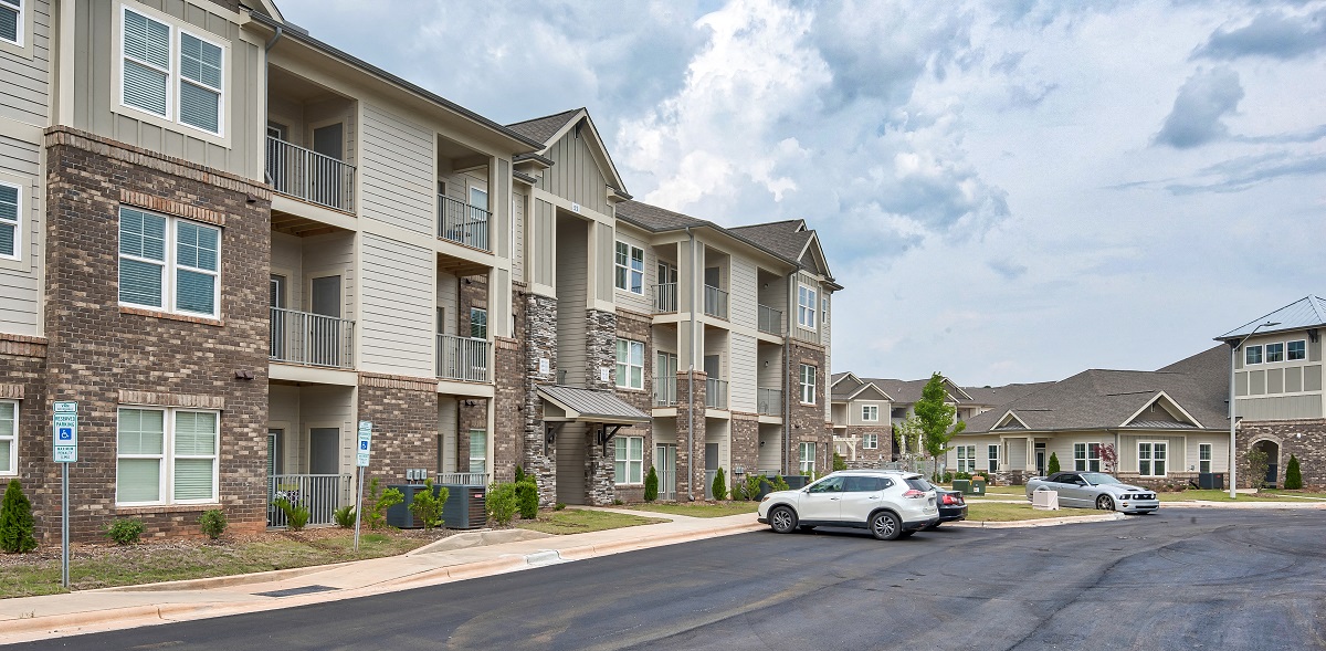 a row of apartment buildings with cars parked outside