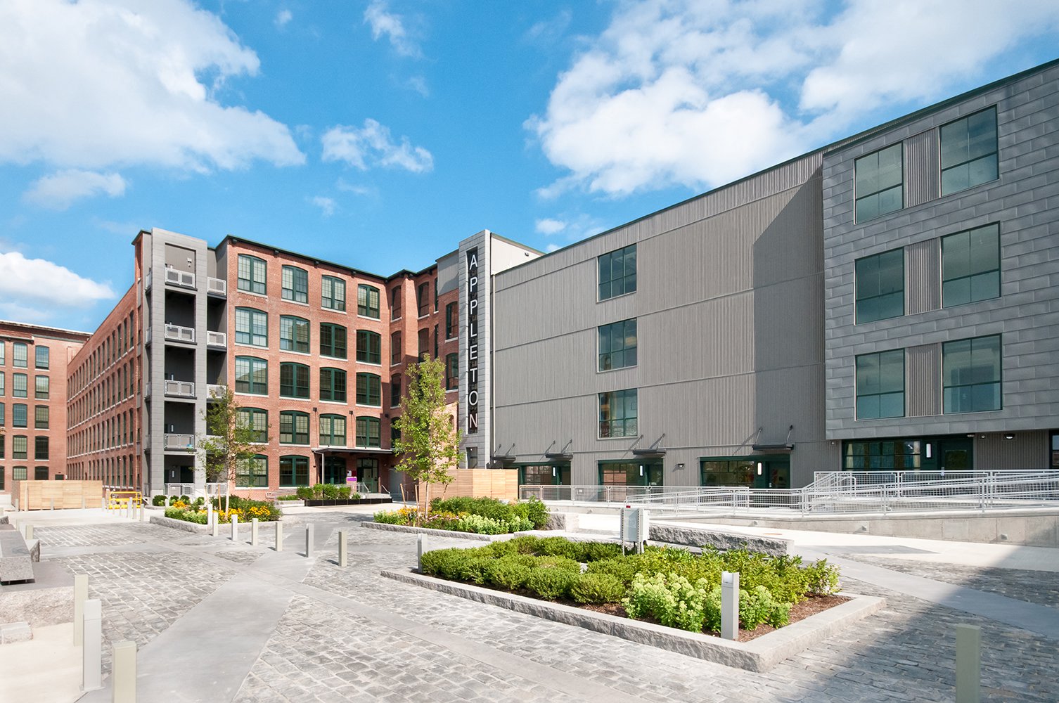 A modern building complex with a cobblestone walkway in front.