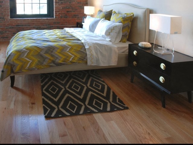 A bedroom with a bed, nightstand, and rug.