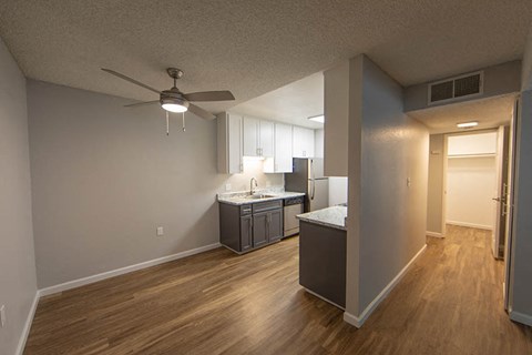 an empty living room and kitchen with a ceiling fan