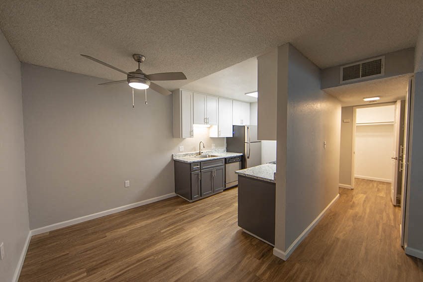 an empty living room and kitchen with a ceiling fan