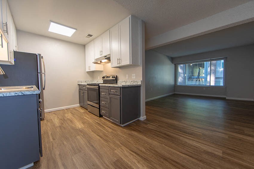 an empty kitchen with stainless steel appliances and wood floors