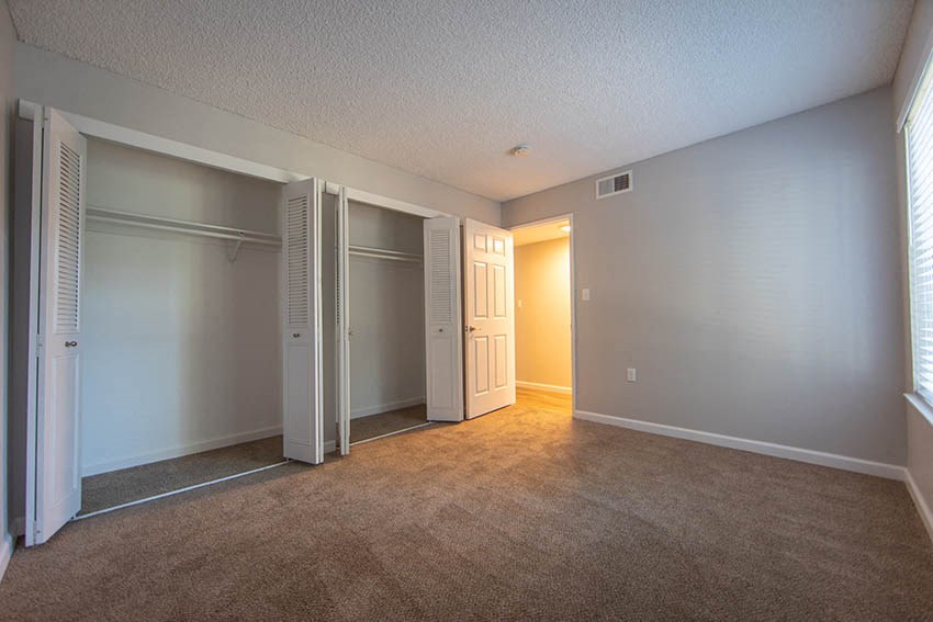 an empty living room with an open door to a closet