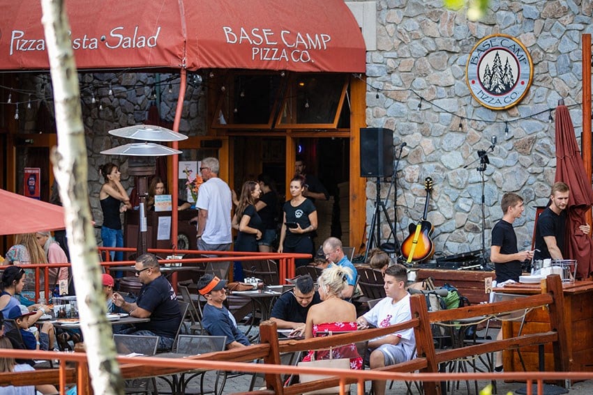 people sitting at tables outside of a pizza restaurant