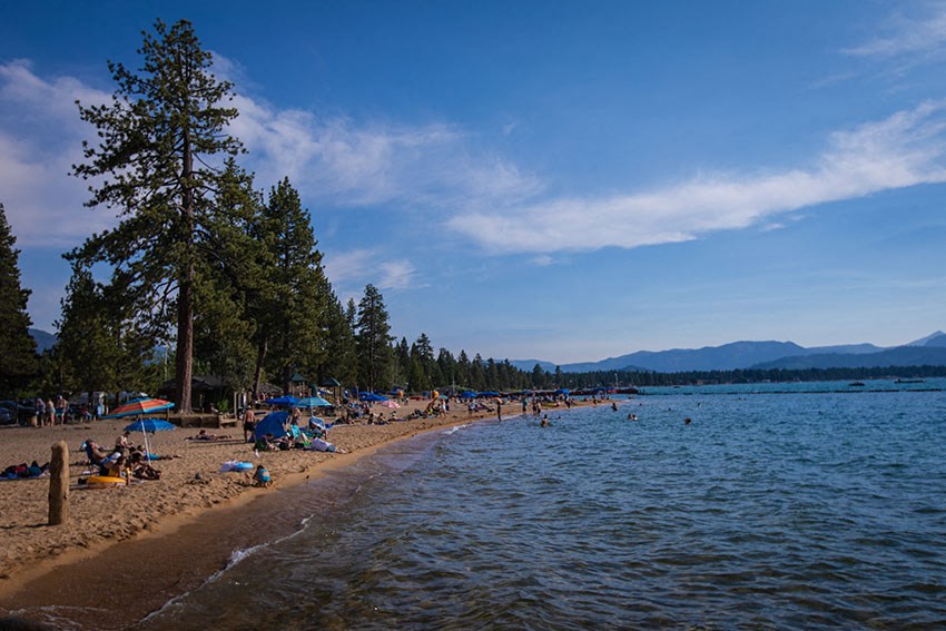a busy beach with people and umbrellas     and the water
