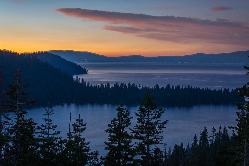 a view of a lake at sunset with trees