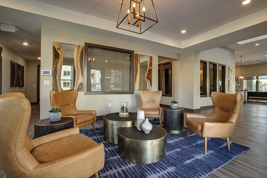 A living room with a large chair and a table with a vase on it.