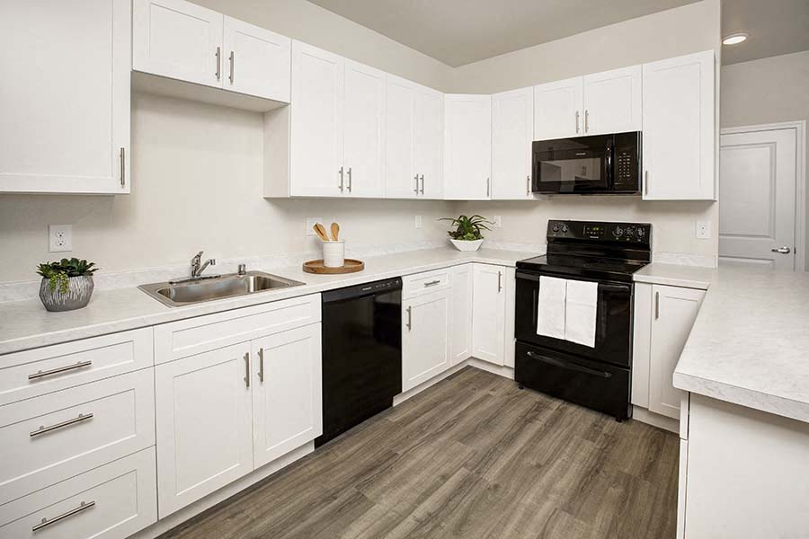 A black oven in a white kitchen with wooden floors.