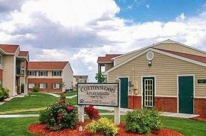 A sign for Cottonwood Apartments is in front of a building.
