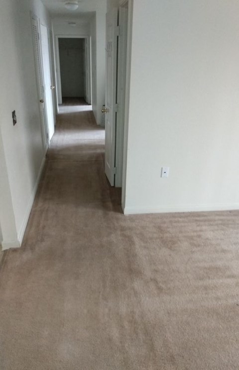 A long hallway with carpeted floors and white walls.
