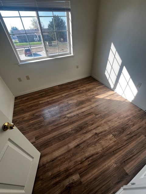A room with a wooden floor and a window letting in sunlight.