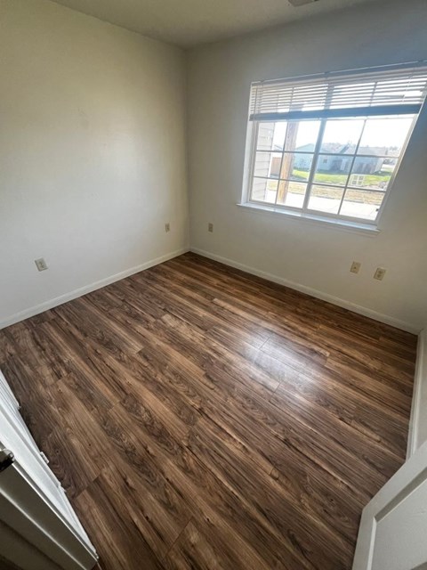 A room with wooden flooring and a window.