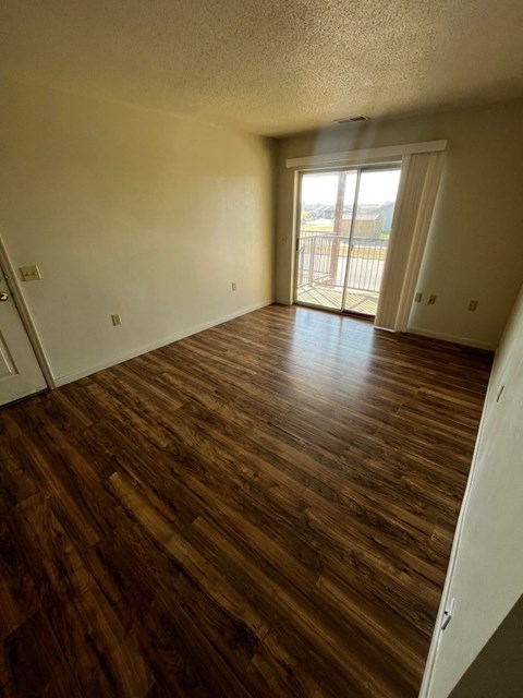 A room with wooden flooring and a sliding glass door.