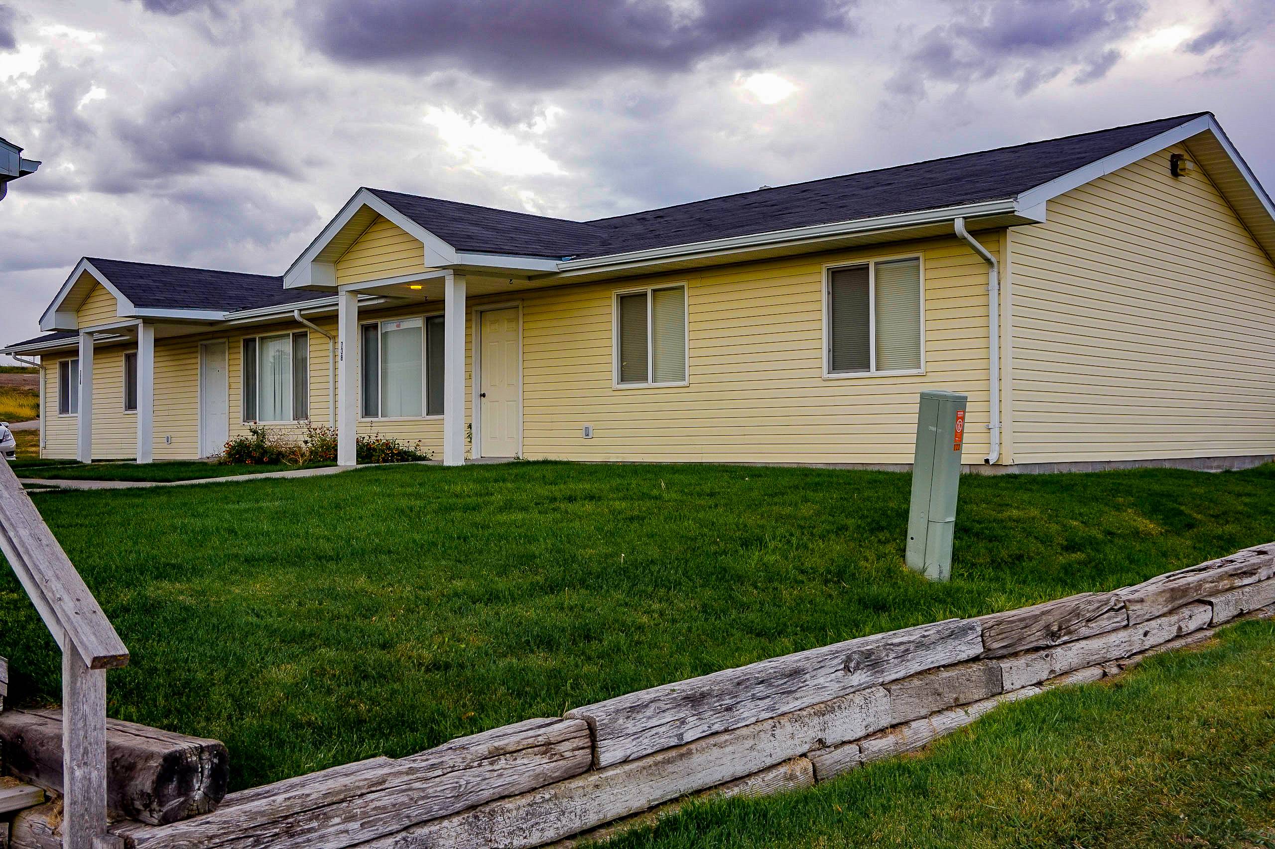 a yellow house with a wooden fence in front of it