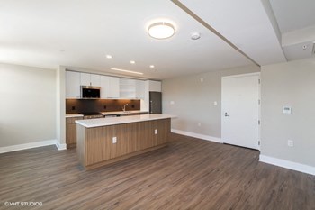 an empty living room with a kitchen in the background - Photo Gallery 18