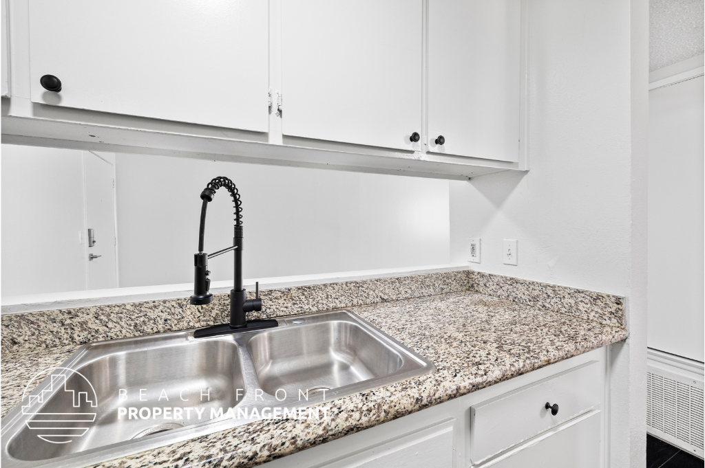a kitchen sink with white cabinets and granite counter tops