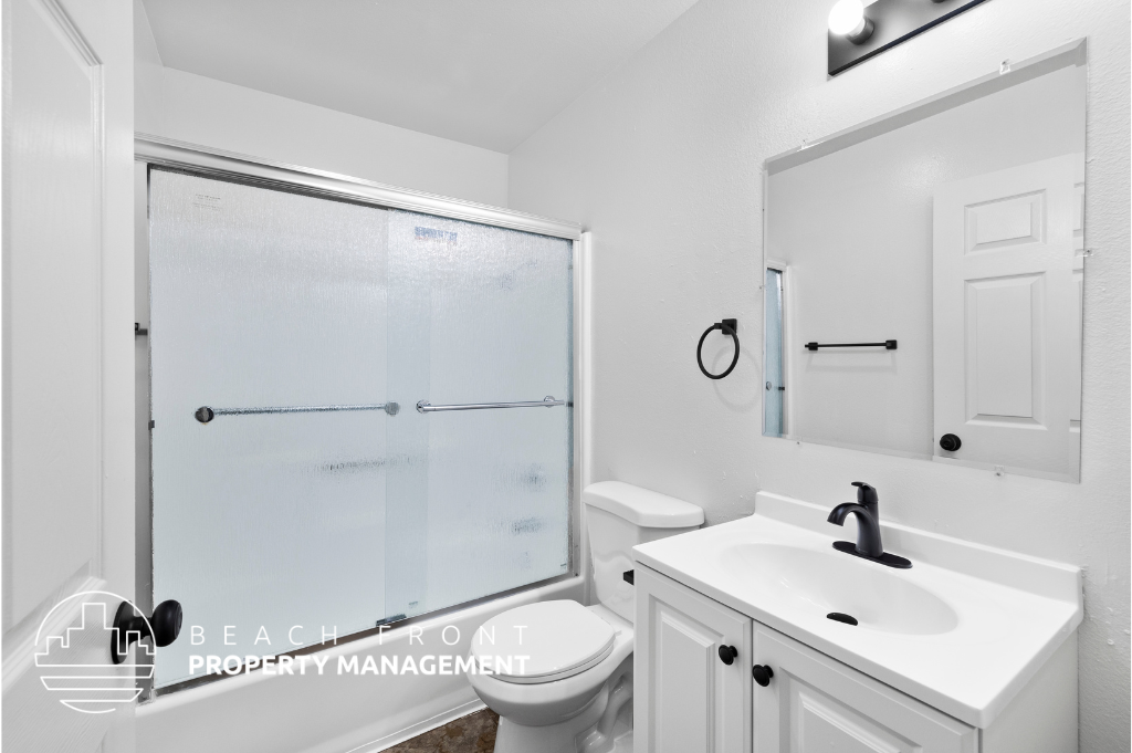 a white bathroom with a sink and a toilet and a shower