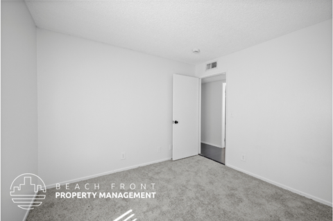 the living room of an apartment with white walls and carpet