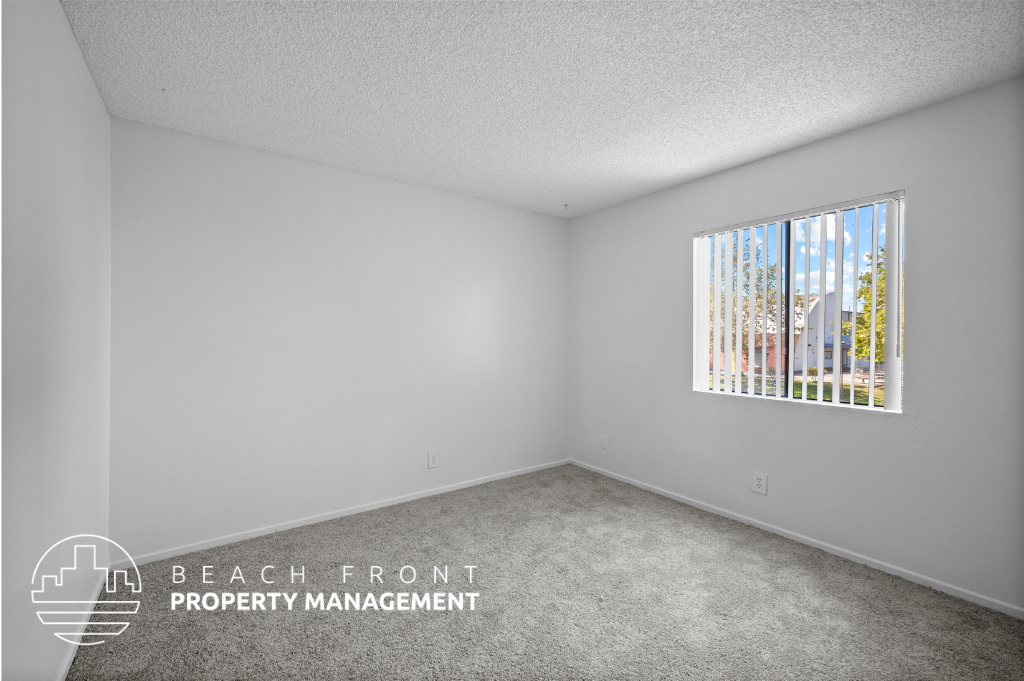 the living room of an apartment with white walls and a window