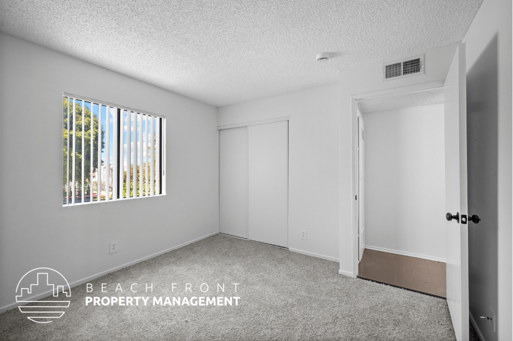 the living room of an apartment with white walls and carpet