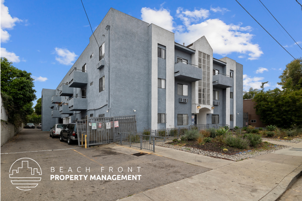 a large grey apartment building with a parking lot and a fence