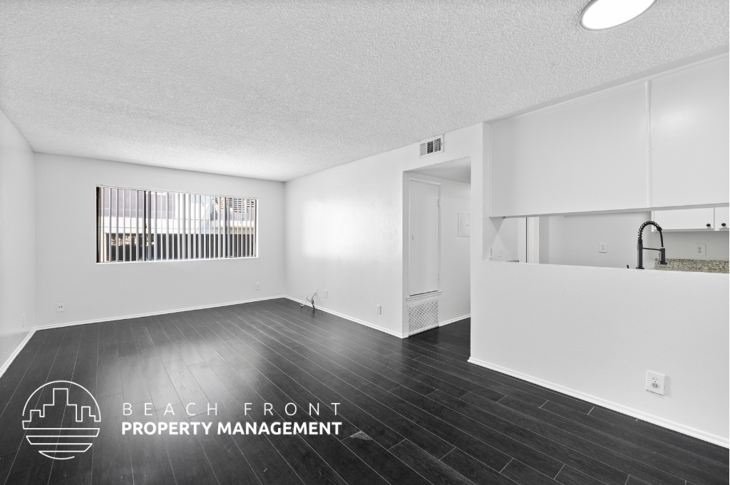 an open living room and kitchen with white walls and wood floors