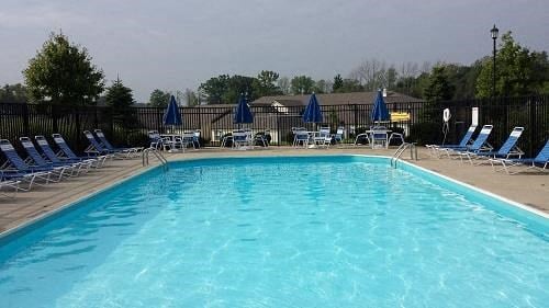 a large swimming pool with blue chairs and umbrellas