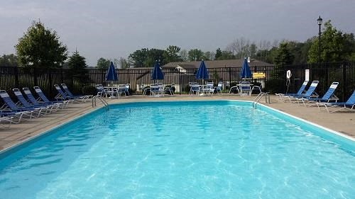a large swimming pool with blue chairs and umbrellas
