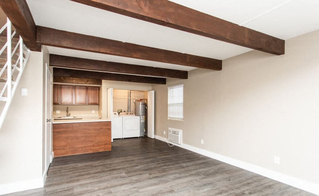 a living room with a kitchen and wooden beams