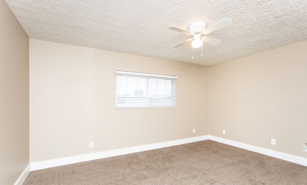 an empty living room with a ceiling fan and a window