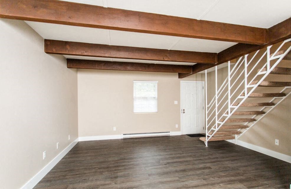 an empty living room with a staircase and wood floors