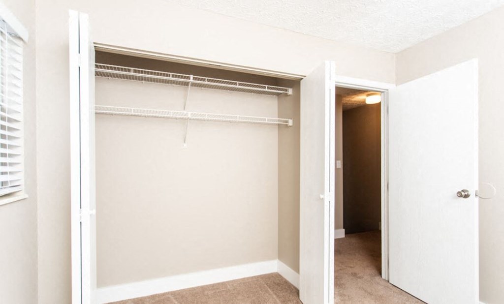 an empty closet in an empty room with a white closet door
