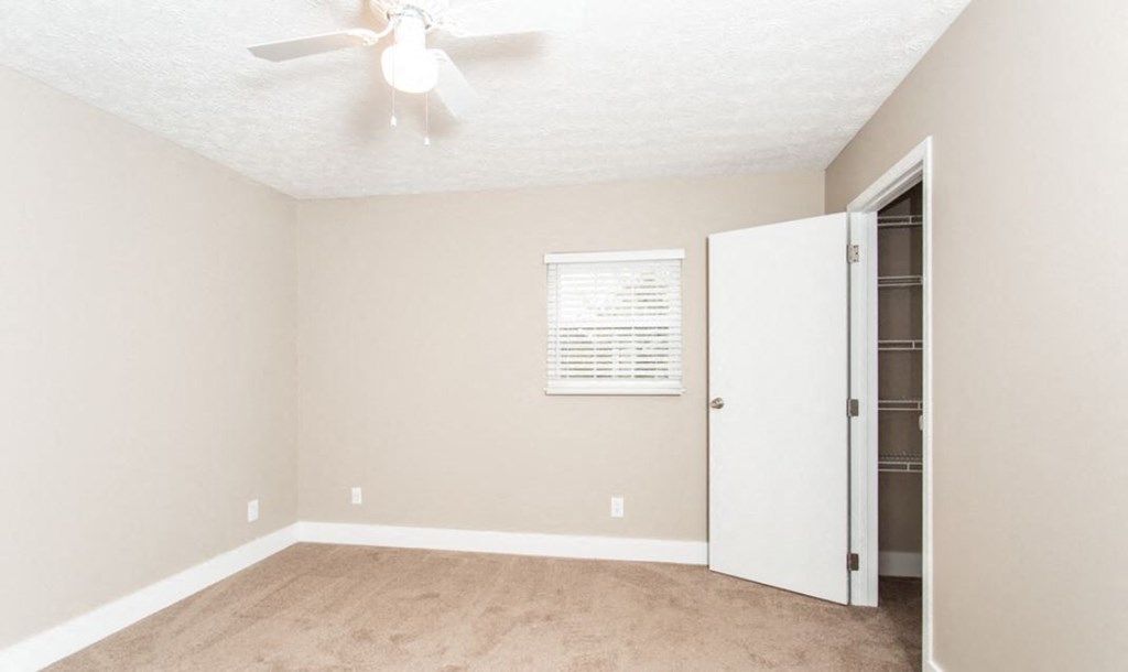 an empty room with a closet and a ceiling fan