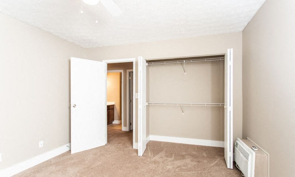 an empty bedroom with a closet with a sliding door