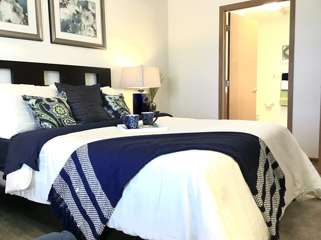 a bedroom with a bed with a blue and white comforter and pillows