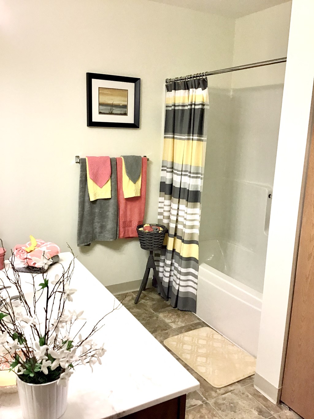 a bathroom with a shower and a table with a vase of flowers