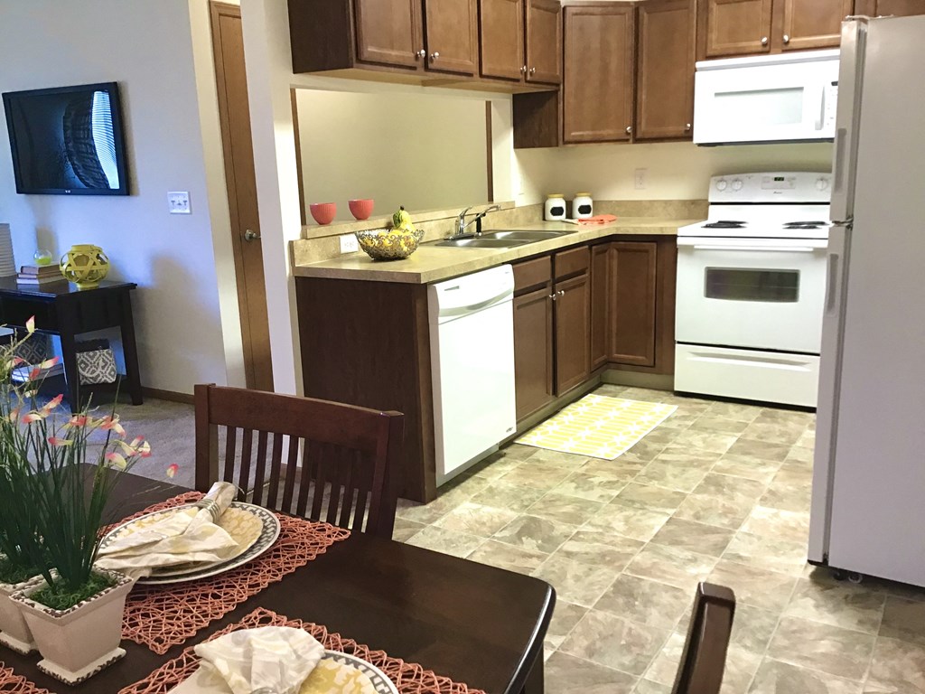 a kitchen with white appliances and wooden cabinets and a dining table