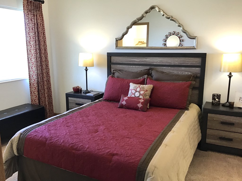 a bedroom with a bed with red pillows and a mirror