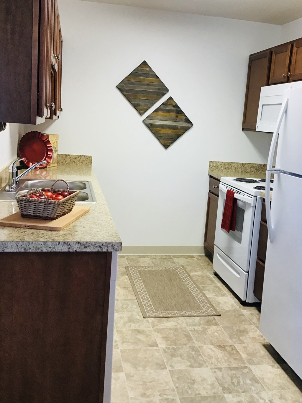 a kitchen with white appliances and a counter with a basket of apples