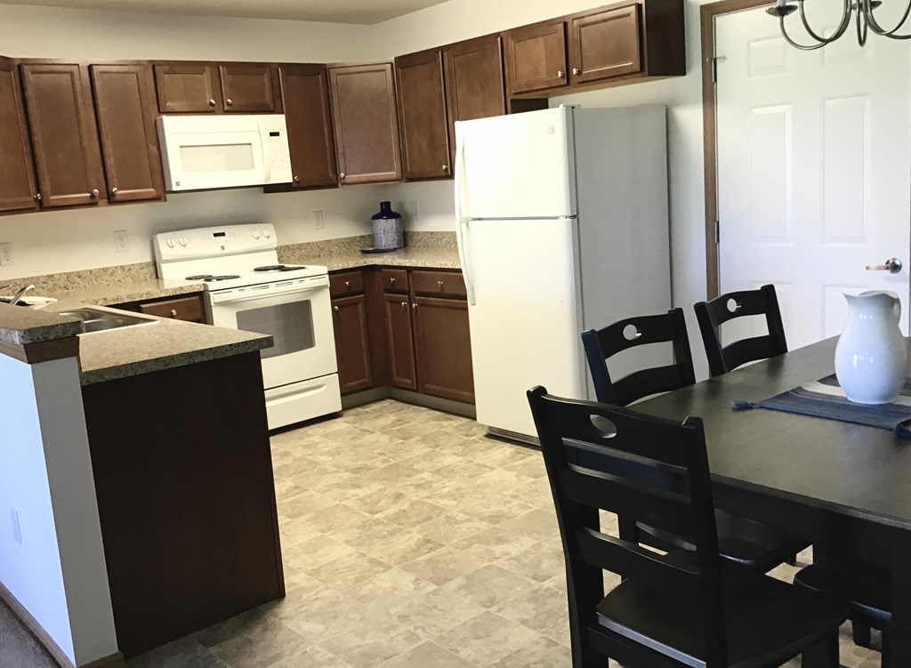 a kitchen with white appliances and a table with chairs