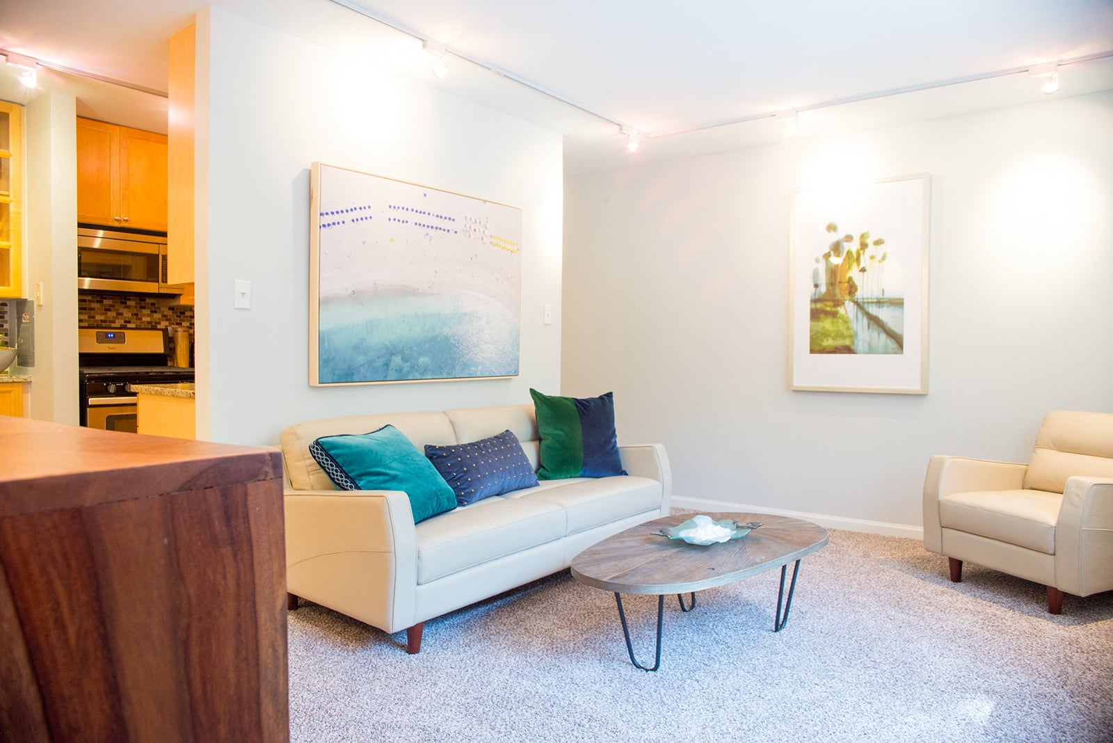 A living room with a white couch and a painting on the wall.